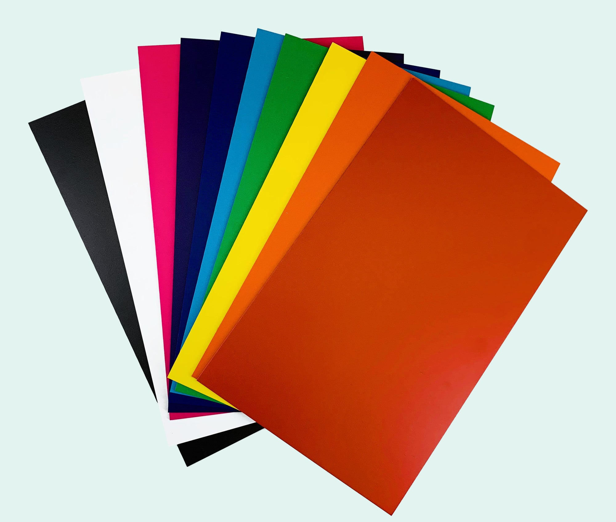 Fan of PatternPly Solids sheets in black, white, pink, navy, blue, green, yellow, orange and red